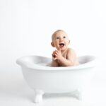 baby inside white bathtub with water