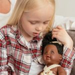 girl in red and white plaid shirt holding a doll